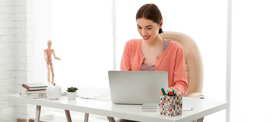 Frau sitzt vor einem Laptop bei einem Schreibtisch von ombra