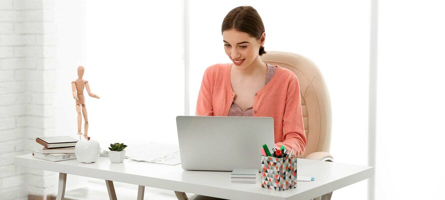 Frau sitzt vor einem Laptop bei einem Schreibtisch von ombra
